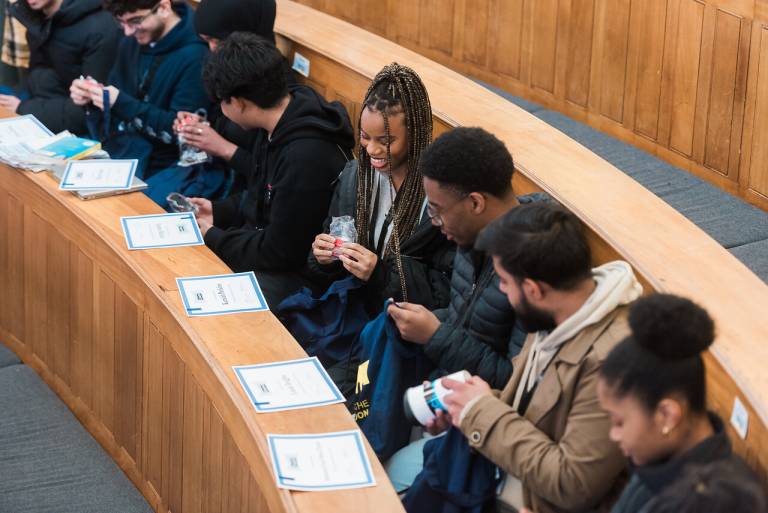 students sitting in a lecture theatre looking at newly gifted certificates